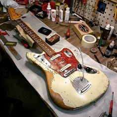 an electric guitar sitting on top of a table next to other tools and supplies in a room