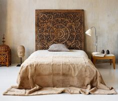 a bedroom with a large wooden headboard on the wall next to a bed covered in a tan bedspread