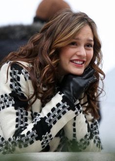 a woman wearing black and white is talking on her cell phone while smiling at the camera