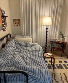 a bed sitting in a bedroom next to a window with curtains on the windowsill