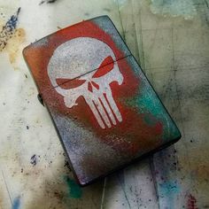 a lighter with a skull painted on it sitting on top of graffiti covered flooring