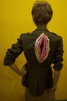 the back of a woman's jacket with an open mouth and pink thread on it