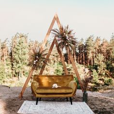 a couch sitting on top of a rug in front of a wooden structure with plants growing out of it