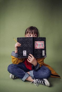 a person sitting on the floor with a laptop in front of their face while holding a pencil