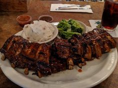 ribs, broccoli and mashed potatoes on a plate with a glass of soda