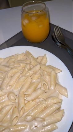 a white plate topped with macaroni and cheese next to a glass of orange juice