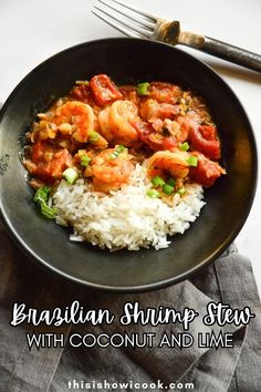 a black bowl filled with rice and shrimp on top of a table next to a fork