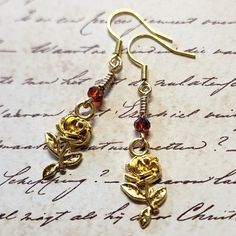 Rose Flower Dangle Earrings with Burgundy Faceted Glass Bead. Dangle approx 2".  Hypo-allergenic gold-tone ear wires. Gold Wire Wrapped Flower Earrings Gift, Gold Drop Earrings With Rose Design, Adjustable Gold Flower Earrings, Gold Dainty Flower Earrings, Adjustable Gold Rose Design Jewelry, Handmade Copper Gold Flower Earrings, Handmade Gold Flower Earrings In Copper, Gold Dangle Flower Earrings With Rose Design, Gold Dangle Earrings With Rose Design