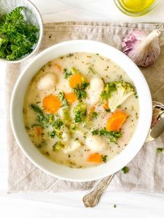 a white bowl filled with broccoli and dumpling soup next to a spoon