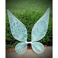 a glass butterfly sculpture sitting on top of a sidewalk next to a lush green bush