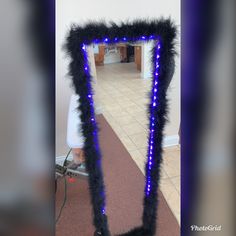 a mirror that has some lights on it in the shape of a frame with feathers