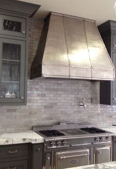 a kitchen with marble counter tops and stainless steel stove top oven, range hood and cabinets