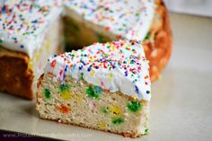 a piece of cake with white frosting and sprinkles