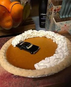 there is a pie with white frosting on it and an orange in the background