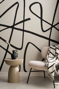 a chair and table in front of a wall with black lines on it