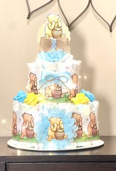 a three tiered baby shower cake with winnie the pooh on it's side