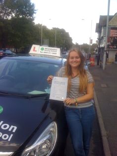 a woman standing next to a police car holding up a paper with the words london school written on it