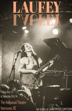 a woman playing guitar on stage in front of a microphone