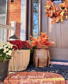 two wicker baskets filled with flowers sit on the front porch next to a welcome mat that says, be yourself you're boss