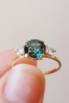 a person holding an engagement ring with a blue and white diamond in it's center