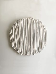 a piece of art that looks like pleated paper is hanging on a white wall