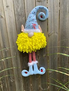 a yellow and blue doll hanging on a fence