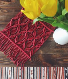 yellow tulips are in a vase next to a red woven placemat on a wooden table