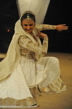 a woman dressed in white and gold is dancing