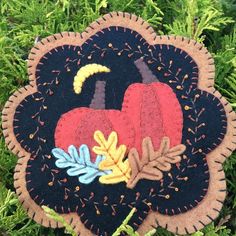 an ornament with two pumpkins and leaves on it sitting in the grass