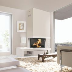 a living room with a fire place in the center and white furniture on the other side