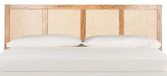 a bed with white sheets and pillows in front of a wooden headboard that has wicker panels on it