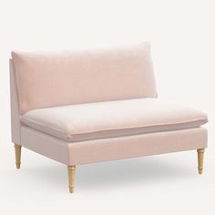 a white couch with wooden legs and a light pink upholstered cushion on it