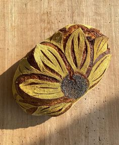 a piece of bread that has been decorated with yellow and brown flowers on it, sitting on a wooden surface