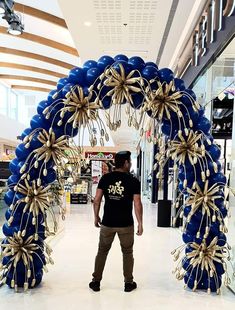 a man standing in front of a blue and gold wreath