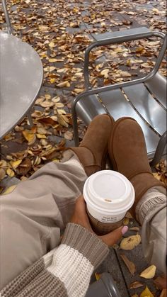 a person sitting on a bench with their feet up and holding a cup of coffee