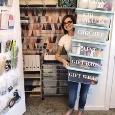 a woman standing in front of a closet with lots of craft supplies