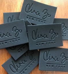 six new york black leather business cards with the name and number on them, sitting on top of a wooden table