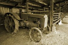 an old farm tractor sitting in the barn