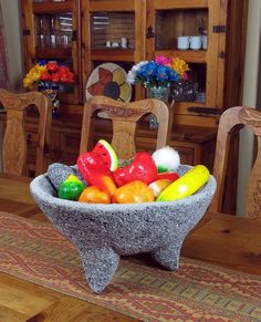 a bowl filled with fruit sitting on top of a wooden table