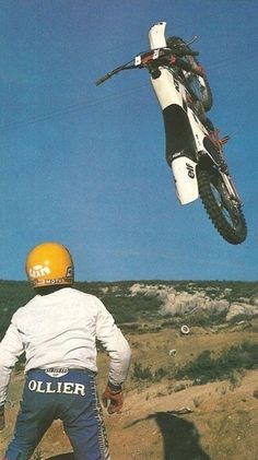 a man flying through the air on top of a dirt bike in front of a motorcycle rider