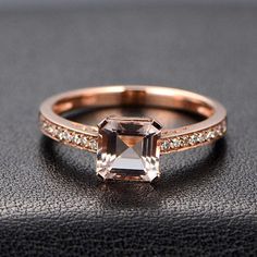 an engagement ring with a square cut diamond in the center and side stones on each band