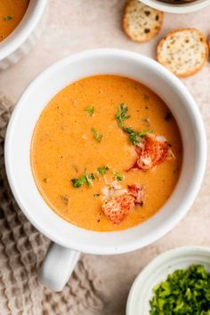 two white bowls filled with soup next to bread