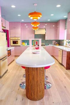 a kitchen with pink cabinets and an island in the center, surrounded by stools