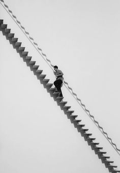 a man standing on top of a ladder next to a kite flying in the sky