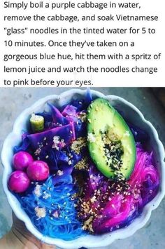 a bowl filled with different colored noodles and an avocado on top of it