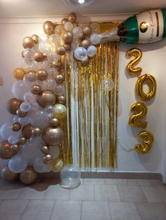 balloons and streamers are hanging from the ceiling in front of a door with a champagne bottle