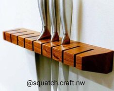 three knives are on a wooden shelf with metal blades hanging from it's sides