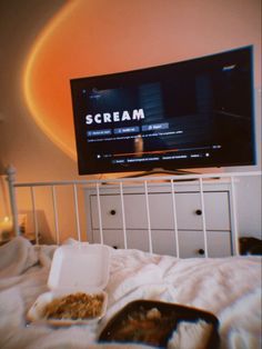 a flat screen tv sitting on top of a white bed