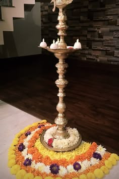 an ornate metal candle holder with flowers and candles on the floor in front of a brick wall