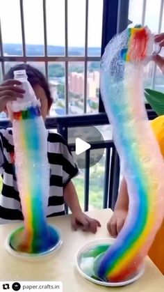 two children are sitting at a table and one is holding a plastic tube in the shape of a rainbow